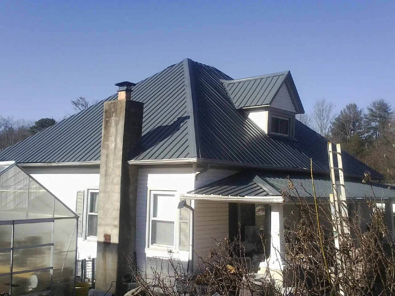 Dark blue standing seam metal roof on a white farmhouse with dormer — Slate & Tile Roof Repair by Roofing Brothers in Scotrun