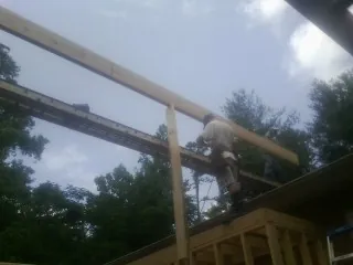 Carpenter setting a ridge beam over a new addition frame — Ice Dam Removal by Roofing Brothers in Scotrun
