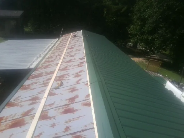 Old rusted panels beside newly installed green metal roofing — Wind Damage Roof Repair by Roofing Brothers in Scotrun