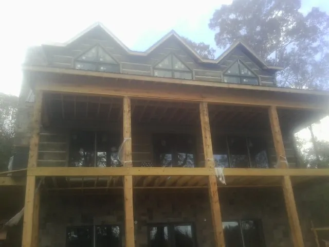 Dormers and porch framing on a large log home under construction — Roof Coating work by our crew in Scotrun