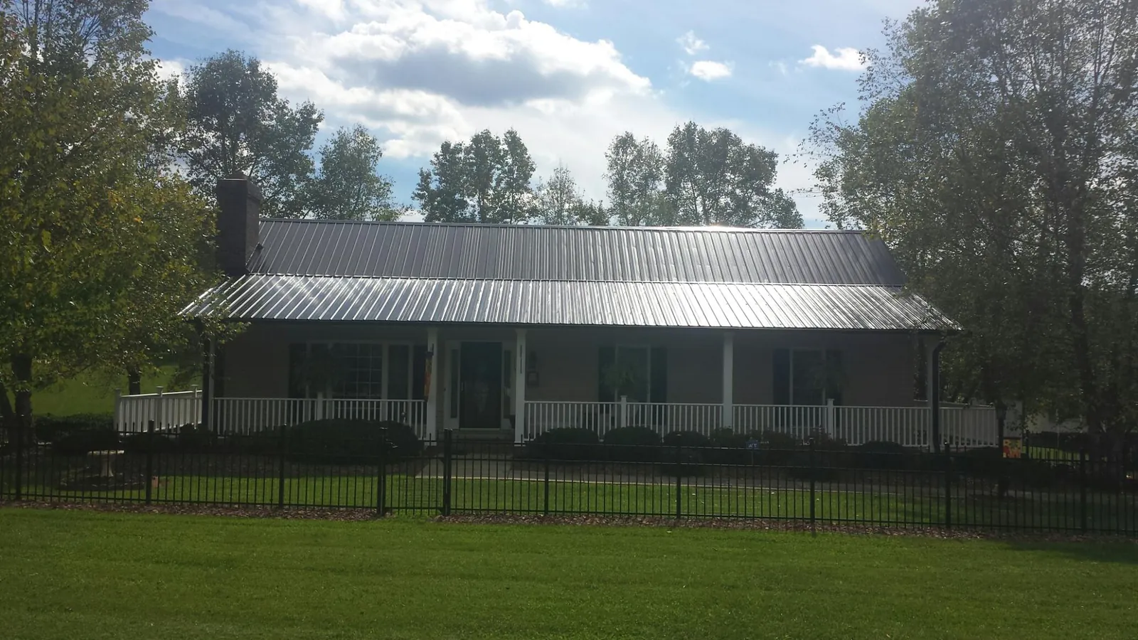 Gray metal roof on a brick ranch with a full width front porch — Gutter Guard Installation work by our crew in Scotrun