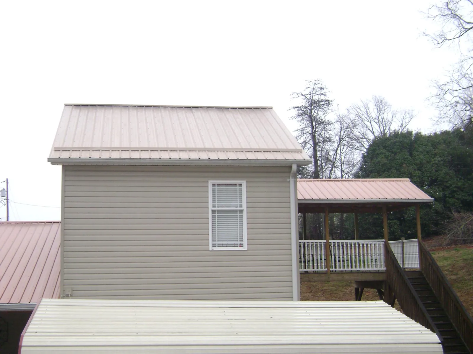 Tan metal roofs on a two story addition and attached porch, from a Roof Replacement job in Scotrun