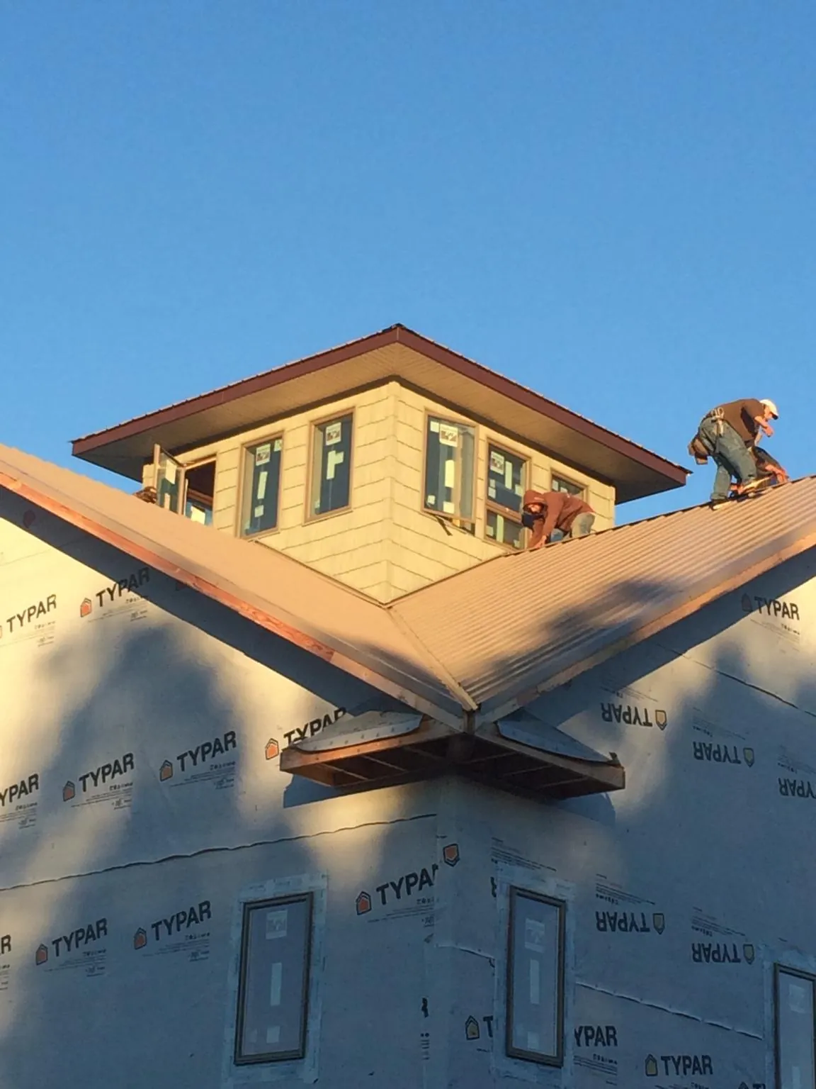 Roofers working around a rooftop cupola on a new metal roof at sunset — Roof Waterproofing in Scotrun by Roofing Brothers